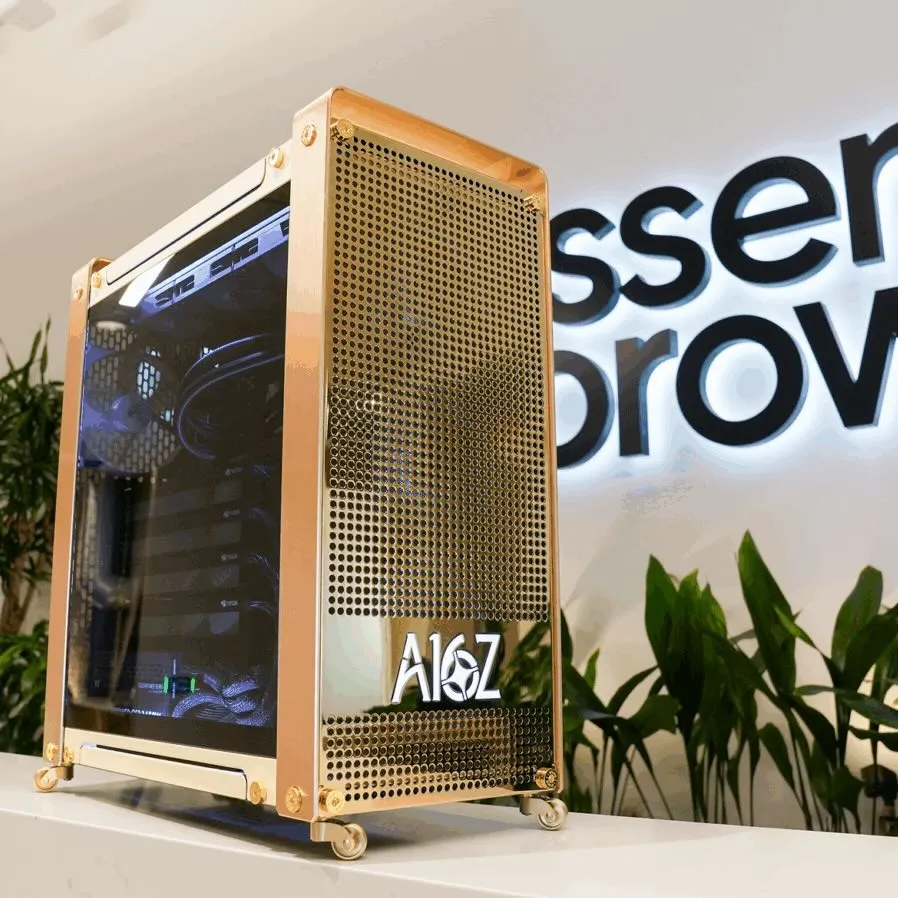 Gold-finished workstation case with perforated panels, a glass side panel, an A16Z logo, and caster wheels, displayed in an office lobby with plants and a backlit sign.