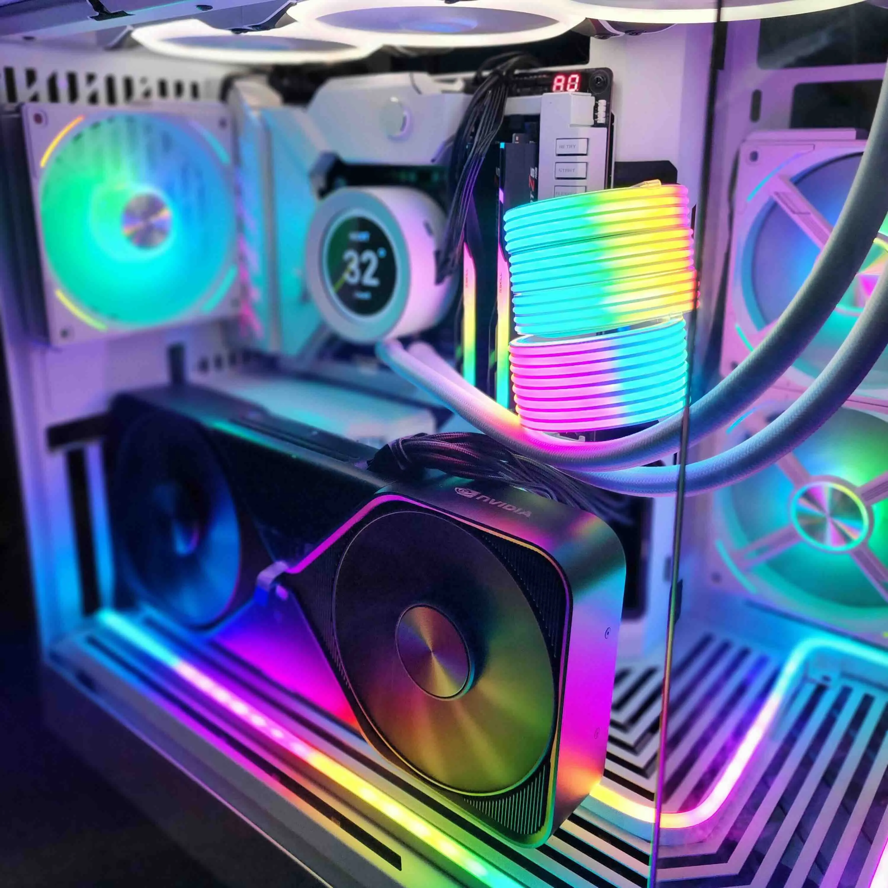 White case interior with a dual-fan NVIDIA reference-style graphics card, an AIO pump with an LCD temperature display, RGB fans, and rainbow-lit power cable extensions.