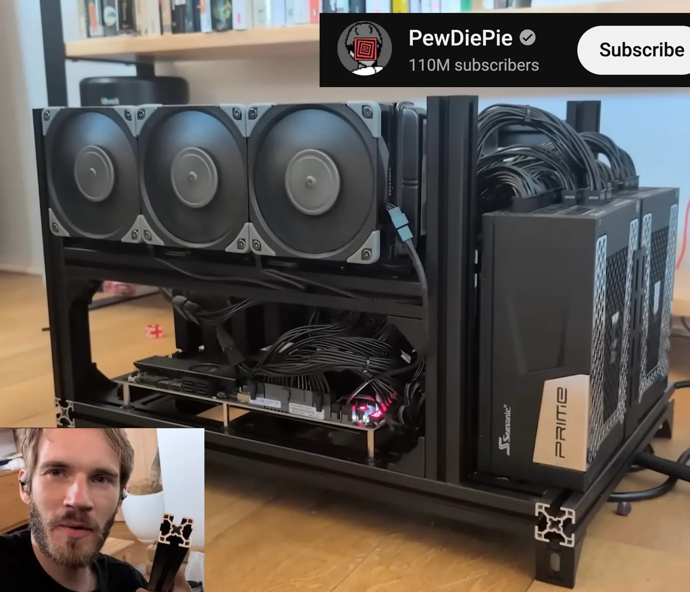 Frame from PewDiePie's video showing his black aluminum-extrusion open rack with three large top fans, dense power cabling, and Seasonic Prime power supplies.