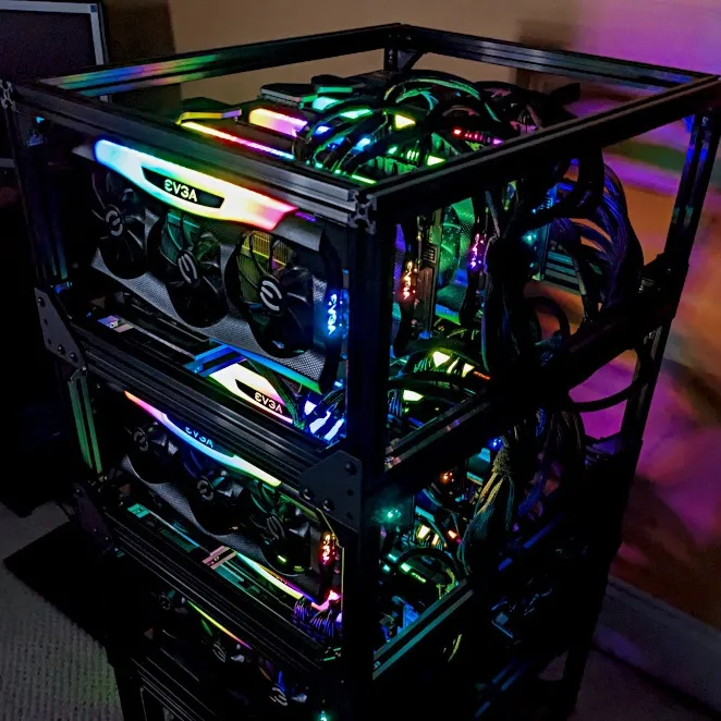 Tall multi-tier black aluminum open frame stacked with EVGA RTX 3090 cards and bundles of power cables, lit with RGB lighting.